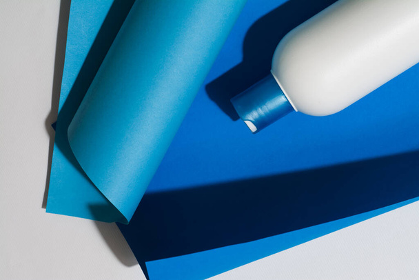 Garrafa de plástico branco, recipiente para cosméticos líquidos, shampoo em fundo azul. Lugar para inscrições e logotipo da marca
. - Foto, Imagem