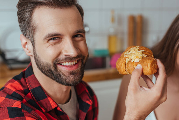 cropped view of girl near happy man holding croissant and looking at camera - Photo, Image
