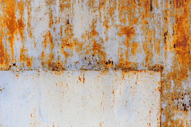 σκουριασμένη επίπεδη μεταλλική επιφάνεια με υπολείμματα λευκής και γαλάζιας μπογιάς, με ορθογώνιο μπάλωμα στη γωνία - Φωτογραφία, εικόνα