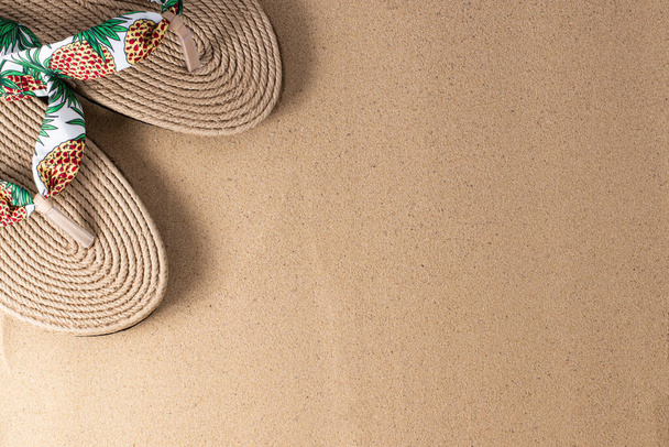 Summer vacation concept. Hat and flip flops on sand background with a copy of space. Summer background. - Photo, Image