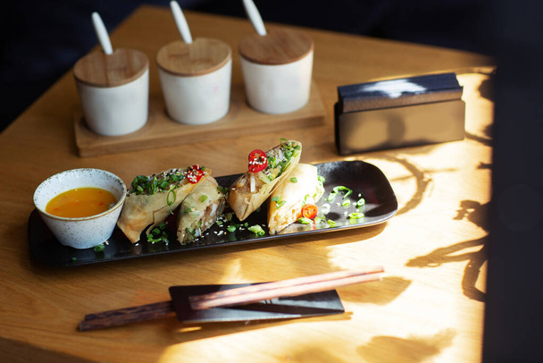 Aasialainen ruoka kevät rullina katkarapuja mustalla lautasella puinen tausta. Paistettua kevätkääryleitä riisipaperilla erilaisia mausteita kastiketta. Ylänäkymä, tilaa tekstille
 - Valokuva, kuva