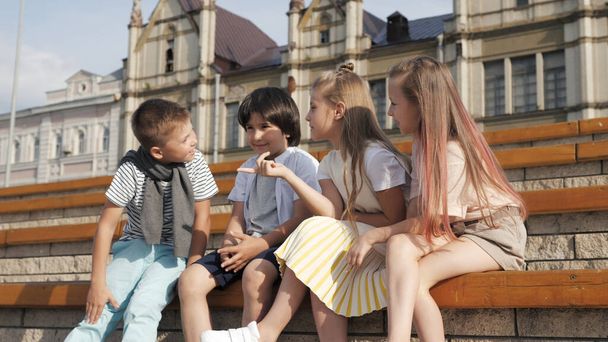 Dört sevimli arkadaş bankta oturan çocuklar konuşuyor.. - Fotoğraf, Görsel