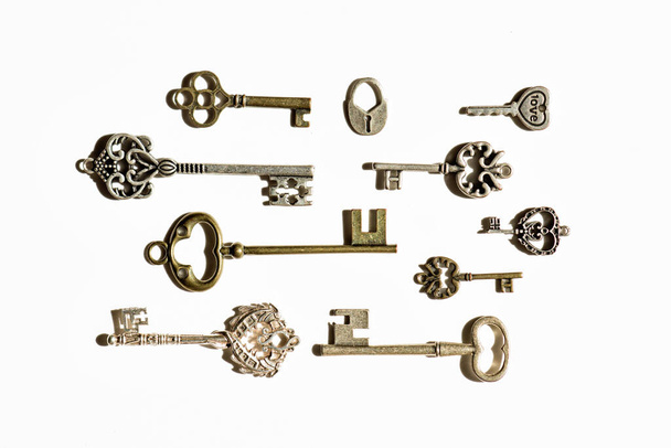 a lot of old, antique keys on a white background, keys from safes, chests, jewelry boxes, differing in shape, color and purpose of keys, the concept of storing wealth, inheritance, secret information - Valokuva, kuva