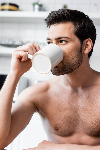 handsome shirtless man drinking coffee on kitchen in morning - Foto, afbeelding
