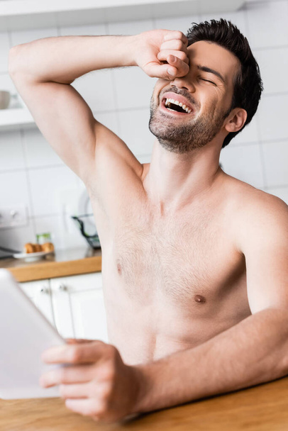 sexy bez koszulki człowiek śmieje się i za pomocą cyfrowego tabletu w kuchni - Zdjęcie, obraz