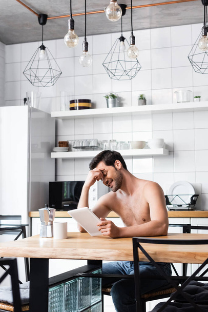 cheerful shirtless man using digital tablet on kitchen with coffee pot and cup - Zdjęcie, obraz