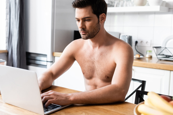 jóképű szexi ing nélküli szabadúszó dolgozik laptop a konyhában  - Fotó, kép