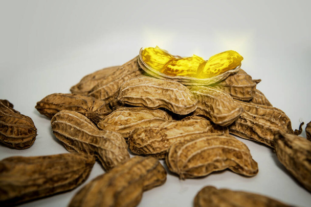 Fantasie. Mutante Erdnüsse sind golden, platziert auf weißem Hintergrund. - Foto, Bild
