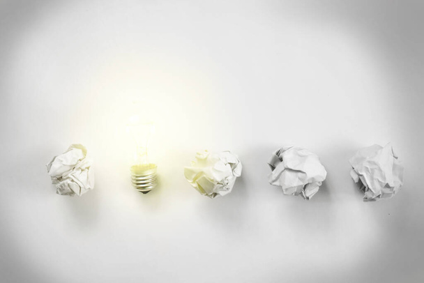 row of paper balls with shining bulb on it. creation concept - Photo, Image