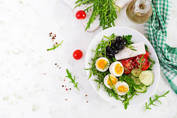 Kahvaltıda. Yunan salatası ve haşlanmış yumurta. Taze sebze salatası, domates, salatalık, zeytin, roka ve peynir. Moda yemeği. Üst manzara, düz uzanma - Fotoğraf, Görsel