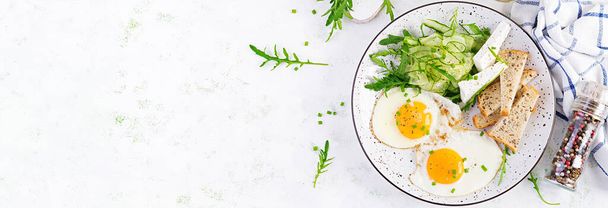 Desayuno inglés: huevos fritos, queso feta, pepino y rúcula. Comida americana. Vista superior, techo, pancarta
 - Foto, imagen
