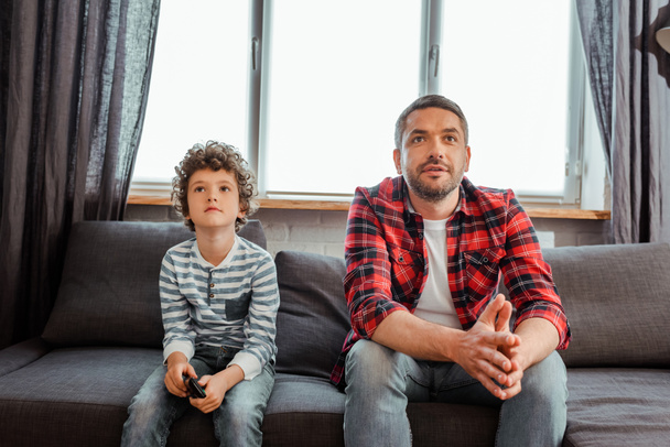 όμορφος πατέρας και χαριτωμένος γιος βλέποντας ταινία στο σαλόνι  - Φωτογραφία, εικόνα