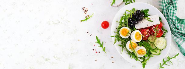 Frühstück. Griechischer Salat und gekochte Eier. Frischer Gemüsesalat mit Tomaten, Gurken, Oliven, Rucola und Feta-Käse. Trendfood. Ansicht von oben, Banner - Foto, Bild
