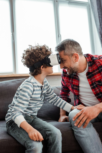 happy father near curly son in virtual reality headset  - Фото, зображення