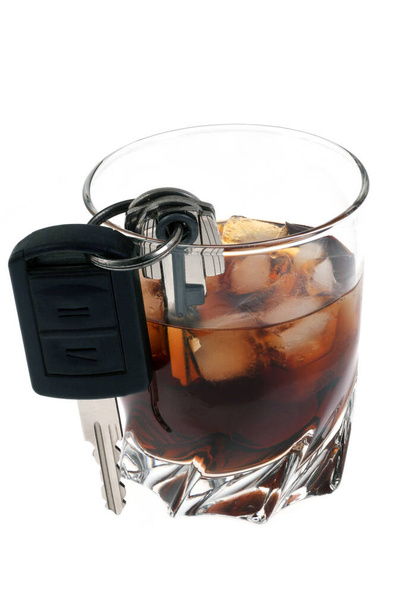 Concepto de beber y conducir con llaves de coche parcialmente en un vaso de alcohol en primer plano sobre fondo blanco
 - Foto, Imagen