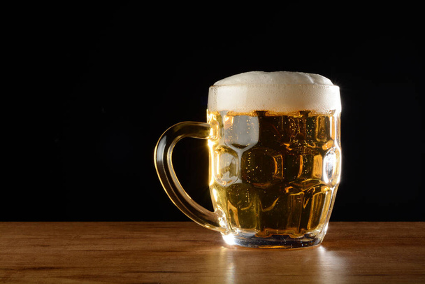 Beer mug on the table, with black background. - Фото, изображение
