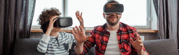 horizontal crop of bearded father and curly son in virtual reality headsets  - Photo, Image