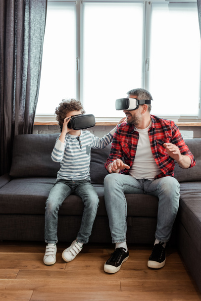 bearded father and cute son in virtual reality headsets  - Фото, изображение