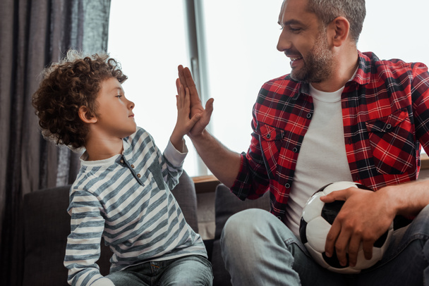 happy father with football giving high five to curly son - Photo, Image