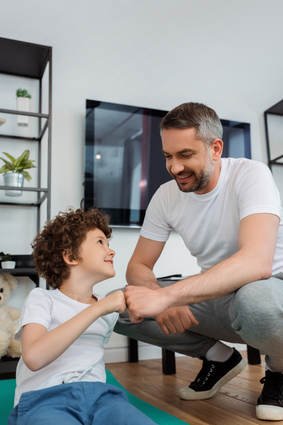 happy father bumping fists with smiling son at home - Photo, image