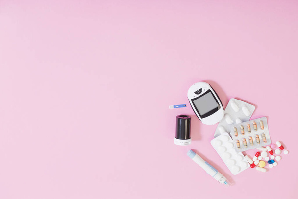 glucometer and pills on  pink background - Φωτογραφία, εικόνα