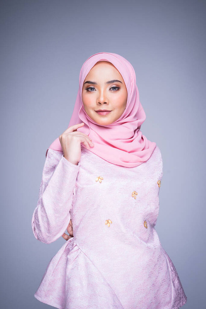 Ritratto a mezza lunghezza di una bellissima modella che indossa abiti tradizionali e hijab, un abbigliamento stile di vita per donne musulmane isolate su sfondo grigio. Idul Fitri e il concetto di moda hijab
. - Foto, immagini