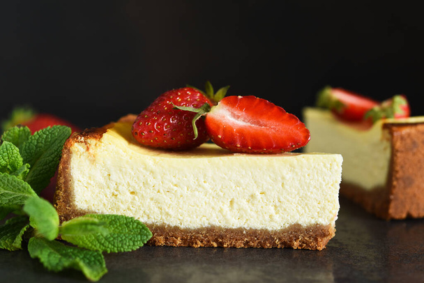 Slice of cheesecake with strawberries and mint on a dark background. Cheesecake New York. Advertising. Restaurant menu. - Photo, image