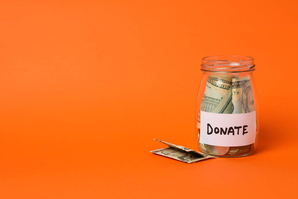 Pot en verre avec argent et texte Faire un don sur fond orange
 - Photo, image