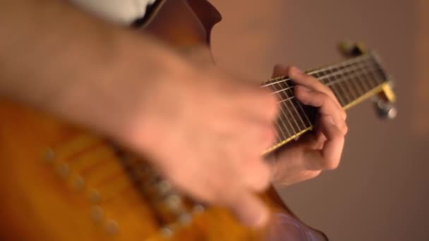 Młody człowiek gra na gitarze elektrycznej w domu. Złota bursztynowa gitara słoneczna. Zbliżenie. - Materiał filmowy, wideo