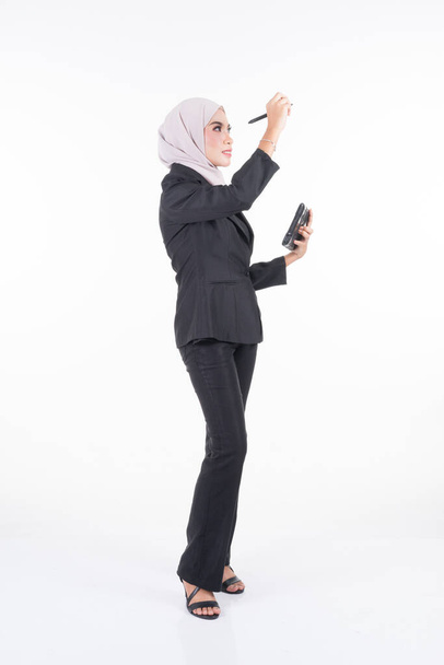 Teljes hosszúságú portré egy vonzó muszlim üzletasszonyról, aki hidzsábot visel tablettával és fehér alapon izolált gesztusokkal. Vállalati, technológiai, üzleti vagy pénzügyi imázsvágáshoz. - Fotó, kép