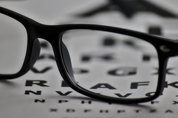 gafas colocadas en una hoja con letras para poder ajustar la vista
 - Foto, Imagen
