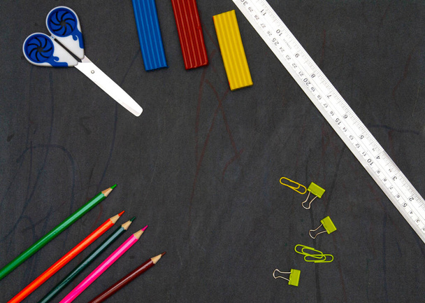 egy táblán olló és egy vonalzó, műanyag és színes ceruzák, gemkapcsok. általános iskolai oktatás. Lapos fekvés. másolás helye. - Fotó, kép