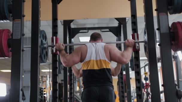 Großer und kräftiger Gewichtheber kauert mit schwerer Langhantel. - Filmmaterial, Video