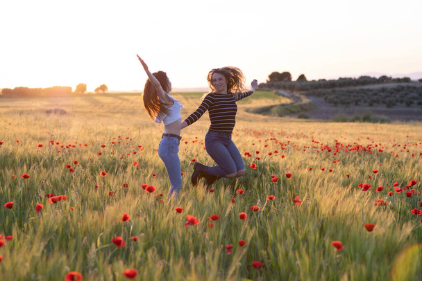 Két lány ugrál napnyugtakor a mezőn. - Fotó, kép