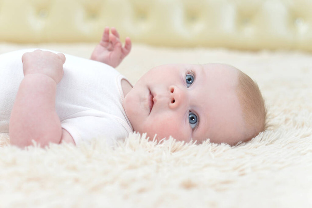 little baby girl lying on fluffy blanket and looking at the camera - Фото, изображение