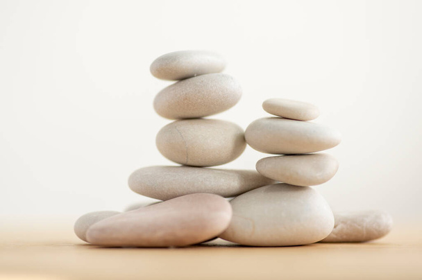 Simplicity stones cairns isolated on white background, group of light gray pebbles built in towers, wooden table, harmony and balance - Photo, Image