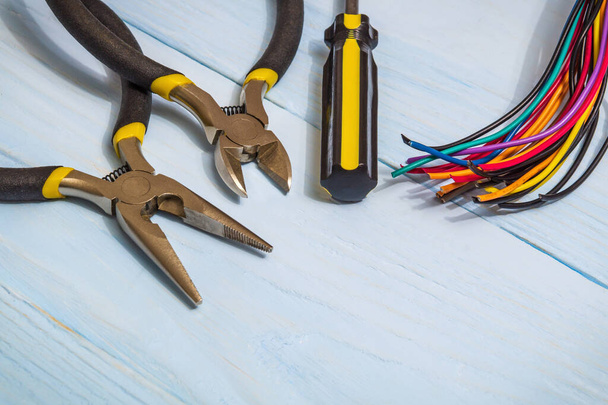 Szczypce narzędzie i wielobarwne druty dla elektryka zbliżenie na niebieskich deskach - Zdjęcie, obraz