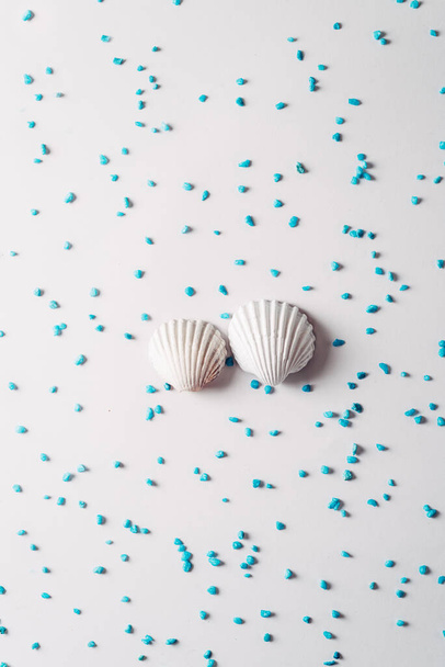 Fehér tengeri kagyló körül kék homok fényes háttér, Nyári idő koncepció - Fotó, kép