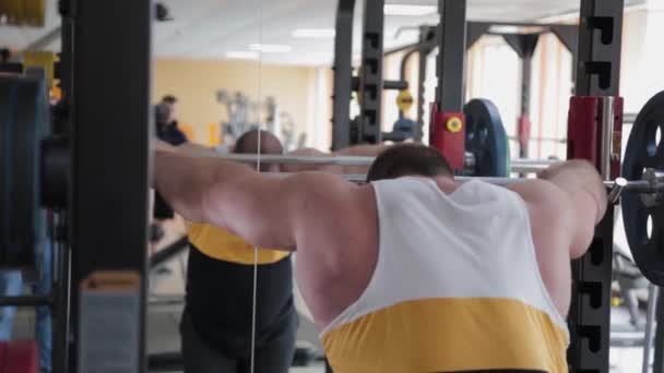 A large and powerful weightlifter is preparing to squat with a barbell. - Filmagem, Vídeo