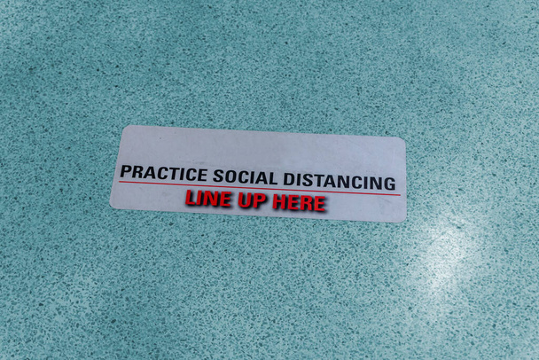 Sociale afstandsinstructie op de vloer van een warenhuis - Foto, afbeelding
