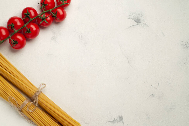Along the left side are cherry tomatoes and two kinds of spaghetti with empty space for text top view - Foto, Imagem