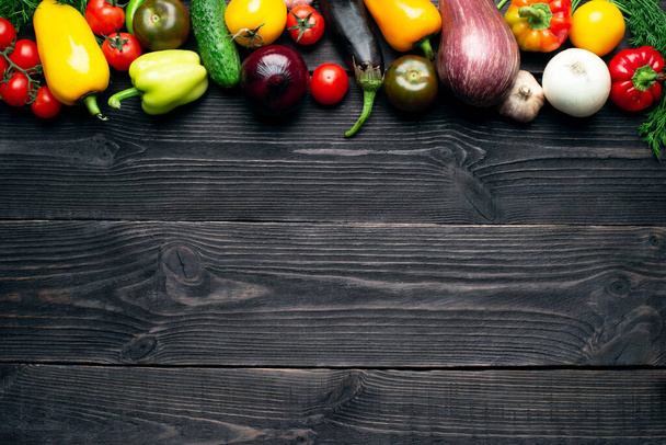 Fresh multi-colored vegetables rich in vitamins on a dark wooden background are located along the edge. Healthy fiber diet top view - Zdjęcie, obraz