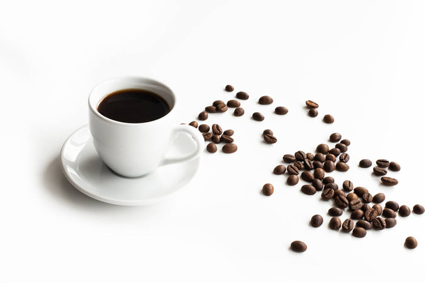 Біла чашка кави і блюдця на білому столі розкидані зерна кави з місцем для перегляду тексту зверху
 - Фото, зображення