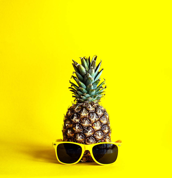 Pineapple on a bright yellow background with yellow glasses - Fotoğraf, Görsel