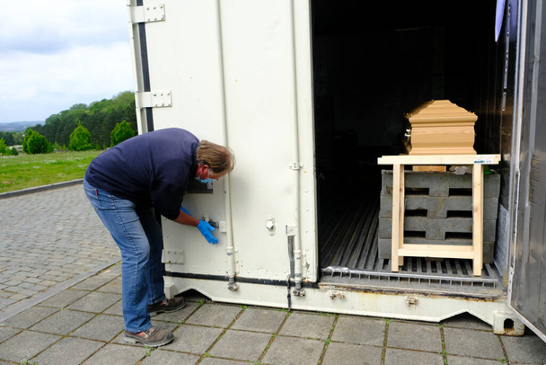 Pracownik komunalny otwiera 29 kwietnia 2020 r. chłodnię zawierającą trumny ofiar COVID-19 na cmentarzu Verrewinkel w Brukseli w Belgii. - Zdjęcie, obraz
