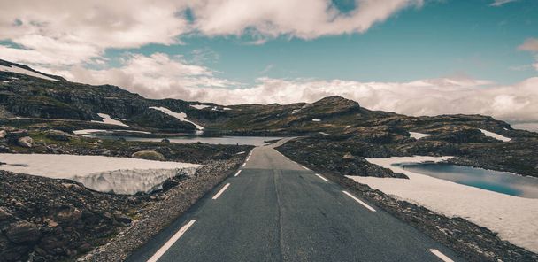 Foto panorámica de la escénica ruta alpina escandinava. Driving Through the Norwegian Amazing Raw Nature. Rocas, nieve, lago y el horizonte
. - Foto, imagen
