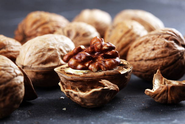 Ядра грецкого ореха и целые здоровые грецкие орехи на деревенском старом столе
 - Фото, изображение