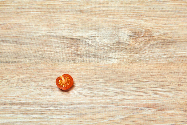 solitario mezzo pomodoro ciliegia sul bordo di una superficie del tavolo in legno
 - Foto, immagini