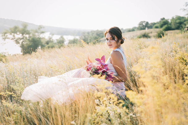 夕日で自然の中で豪華な白とピンクのウェディングドレスで花嫁 - 写真・画像