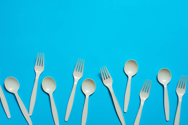 biodegradable disposable forks and spoons of corn starch on a blue background. eco friendly concept. place for text. picnic dishes made of modern materials instead of plastic. - Photo, Image